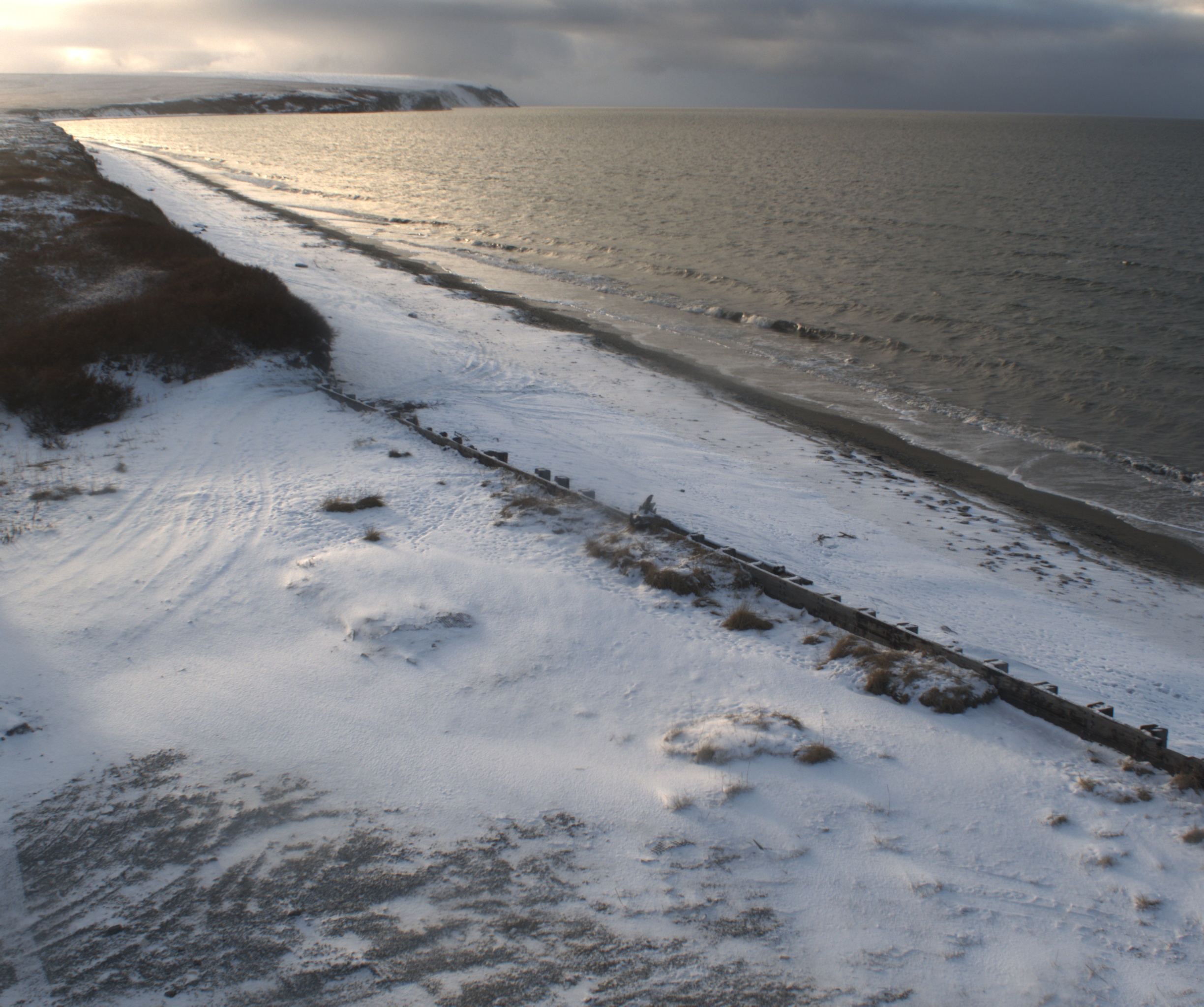 Image from Teller, AK camera 1 showing snowy coast and ocean, looking southwest down the coast.