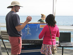 Kurt Rosenberger shows a young visitor how a current meter (suspended in tank) measures the speed and direction of currents and displays the readings on a monitor (right). USGS photograph by Helen Gibbons.