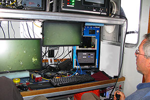 Photo of scientist remotely maneuvering camera system over seafloor.