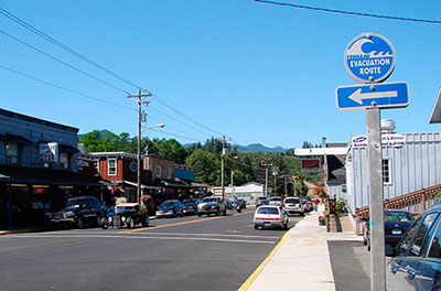 Photograph of the city of Nehalem, Oregon, showing a street with the internationally adopted tsunami-evacuation sign.