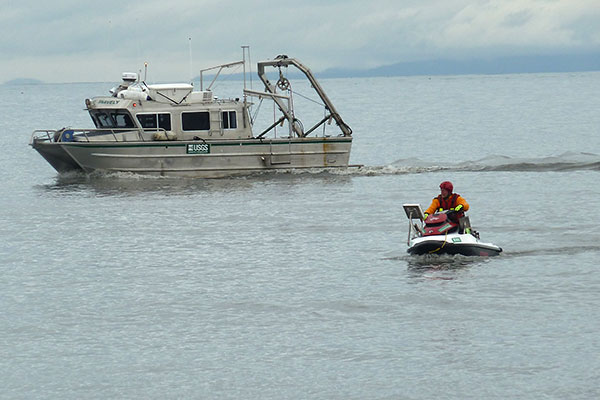 Photograph of USGS research vessel Snavely and a USGS scientist operating a PWC equipped with echosounders to map the nearshore.