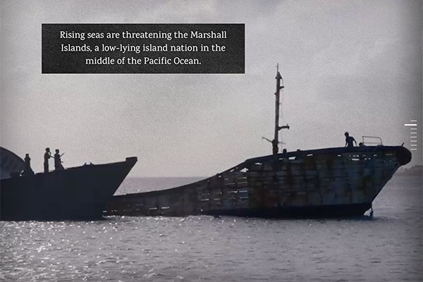 Screenshot from interactive documentary shows two broken ship hulls in shallow water with people on them.