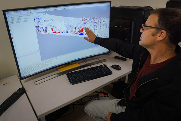 Photograph of Jon Warrick sitting at his computer and explaining structure-from-motion.