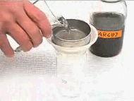 Image shows analyst splitting sample with a 20-micron sieve.