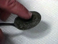 Sample manually being spread into thinner layer on tablespoon.